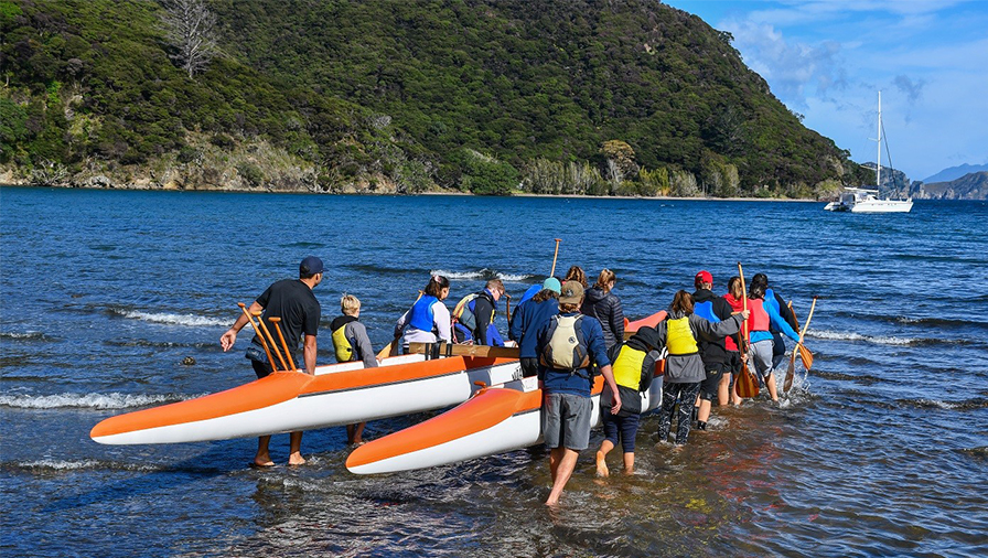 Participants with a waka ama at the Hillary Outdoors Great Barrier Island Centre